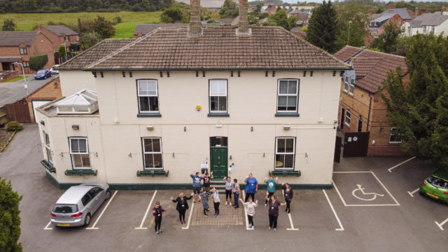 Aerial shot of Homefield College main site, with staff and students standing in front waving