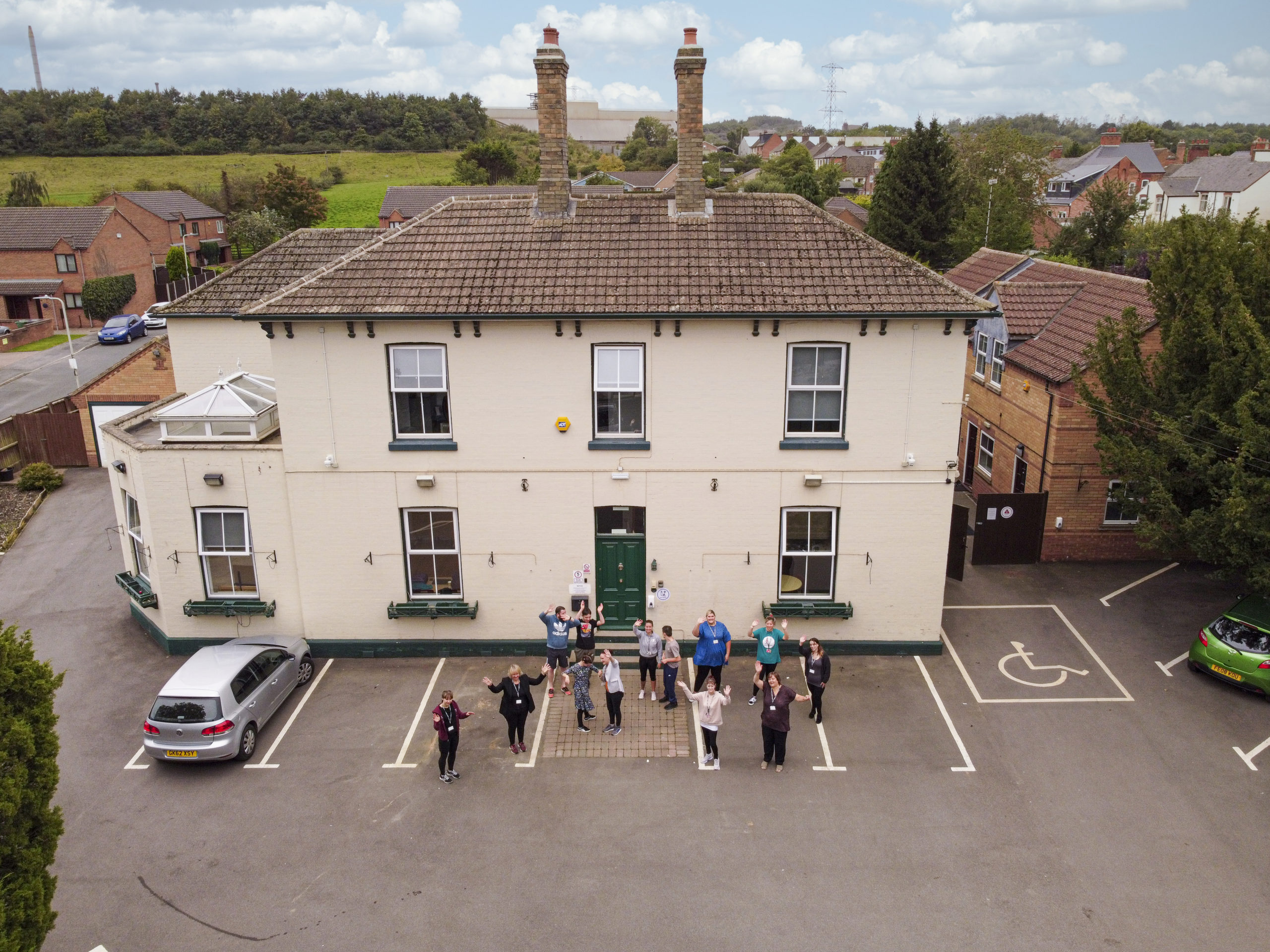 Aerial shot of Homefield College main site, with staff and students standing in front waving