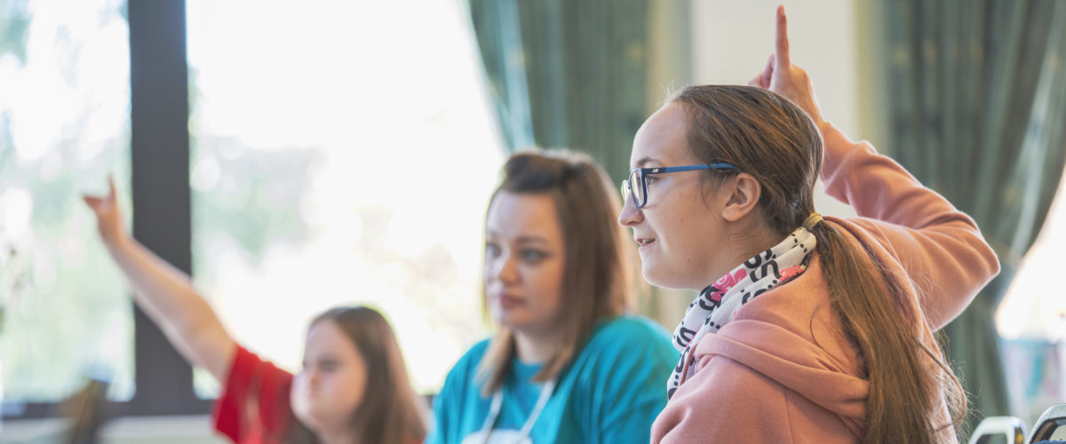 Students with their hands raised waiting to answer questions