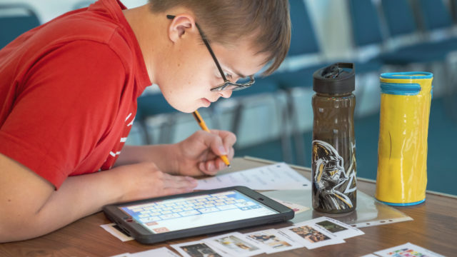 Student using ipad to help answer worksheet